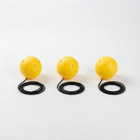 Three optic yellow 40-hole PickleBall Pro replacement pickleballs, each with a coiled black elastic cord, on a white studio background